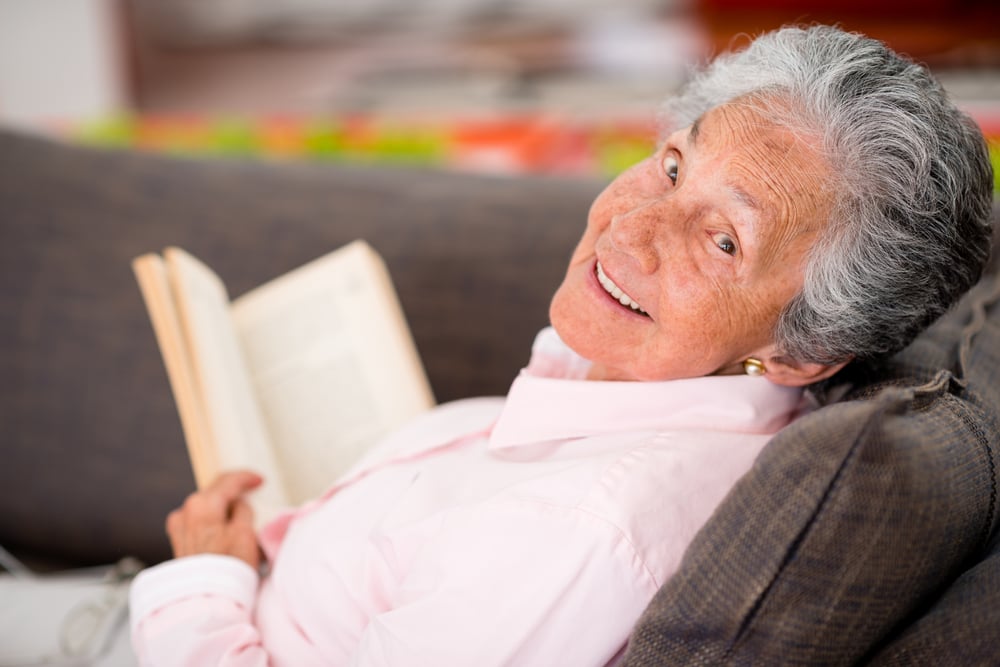 Senior woman reading a book at home enjoying her retirement